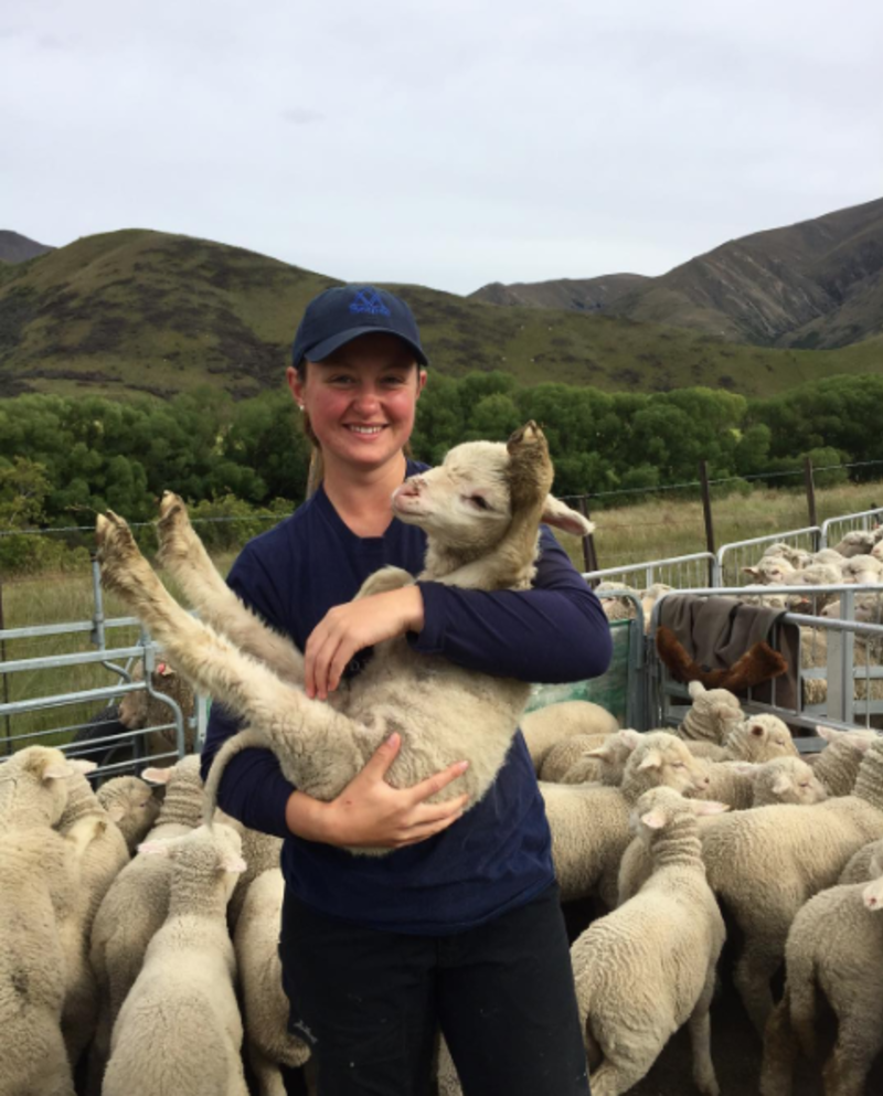 Farmstay girl holding a lamb with hills in the background