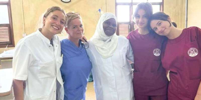 Five smiling women wearing scrubs.