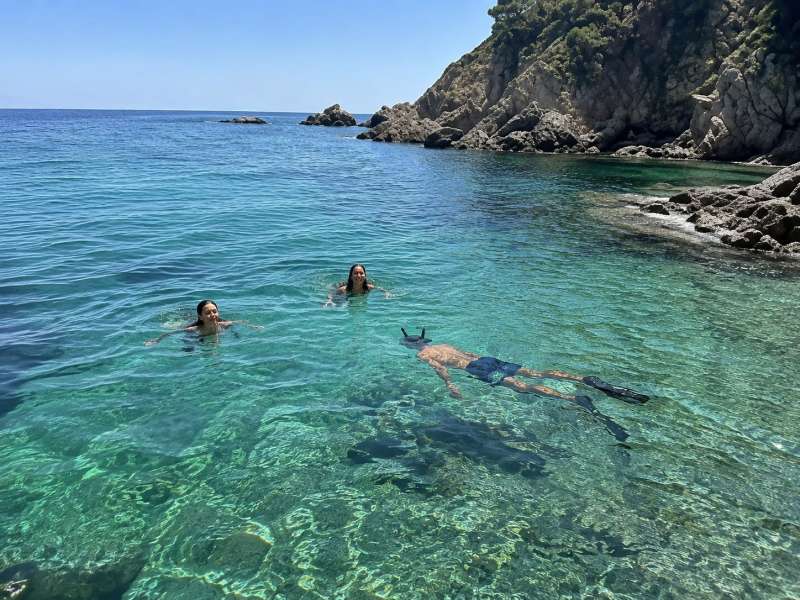 Friends swimming and snorkelling in a clear Spanish cove