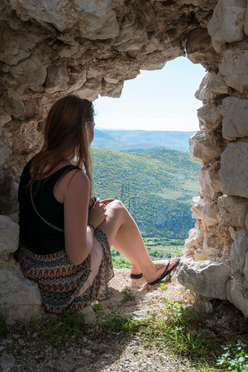 Girl looking out of a view through a rock opening