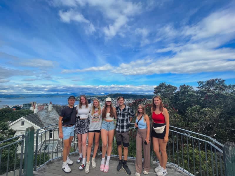 Group of people smiling with views of Auckland + the ocean in the back