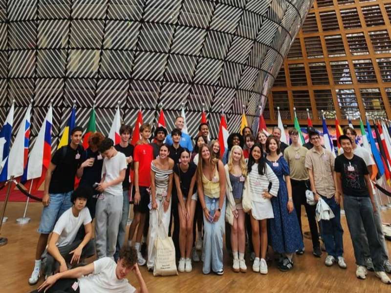 Group photo of students in front of flags in government building in Brussels