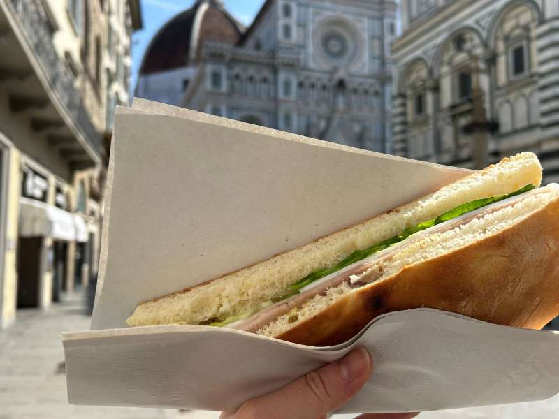 hand holding sandwich in front of Duomo in Florence