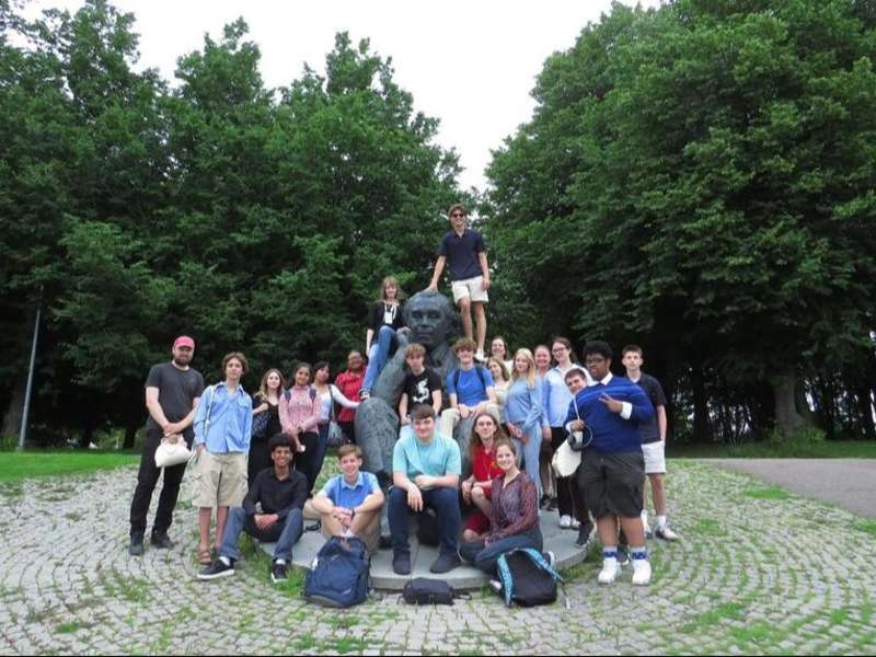 High school participants posing in front of statue in park in Tallinn