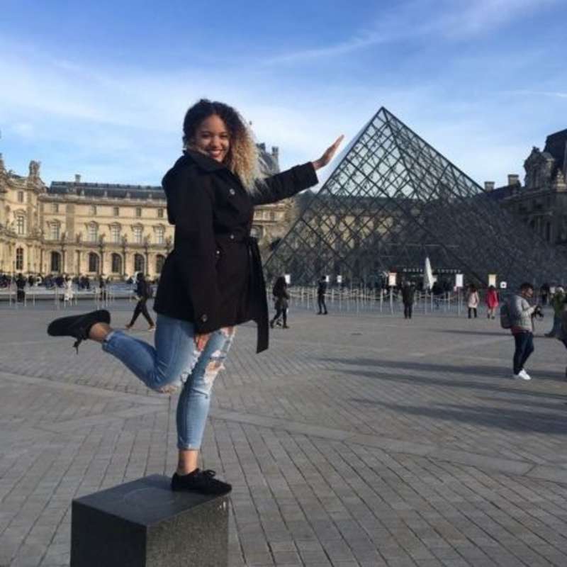 High school student studying abroad posing with the Louvre pyramid
