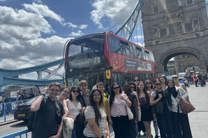 High school students posing by double-decker bus in London