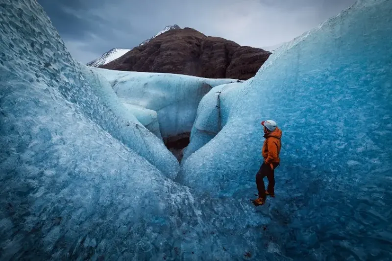 Hiker stands in mountain Ice cavern