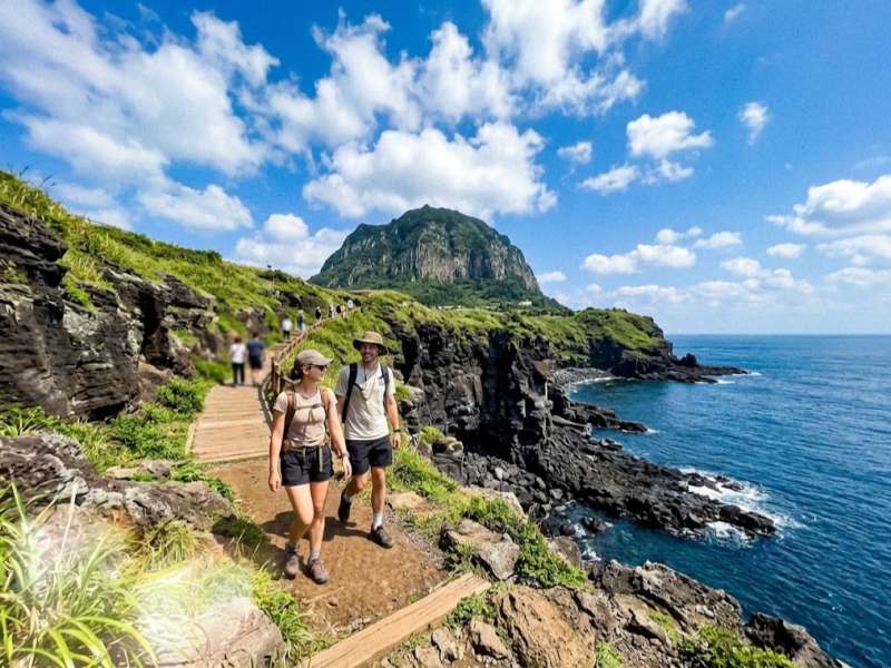 Hikers along the green volcanic cliffs of Seongsan Ilchulbong