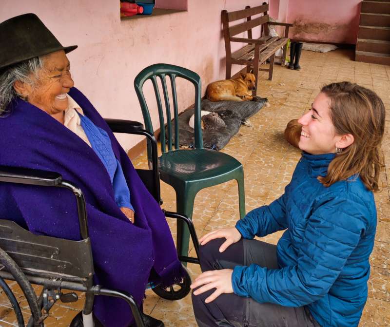 Indigenous Ecuadorian woman in wheelchair smiling with young European intern