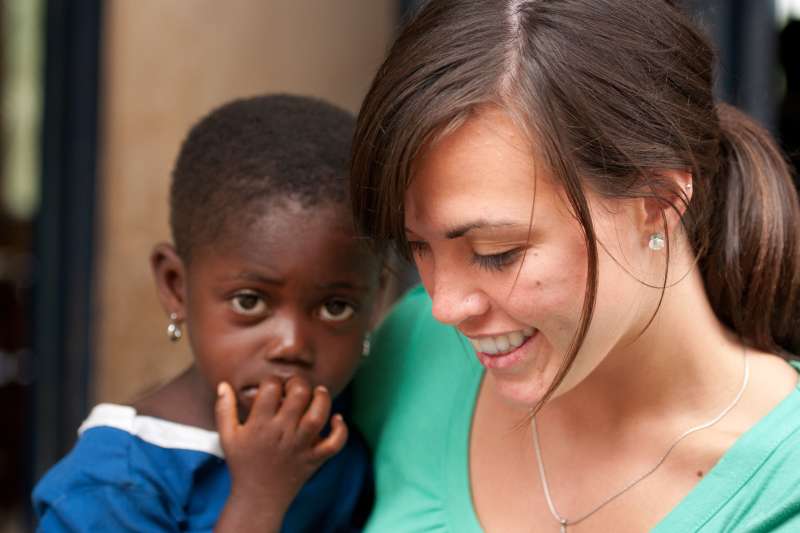 Volunteer with a child putting fingers in her mouth