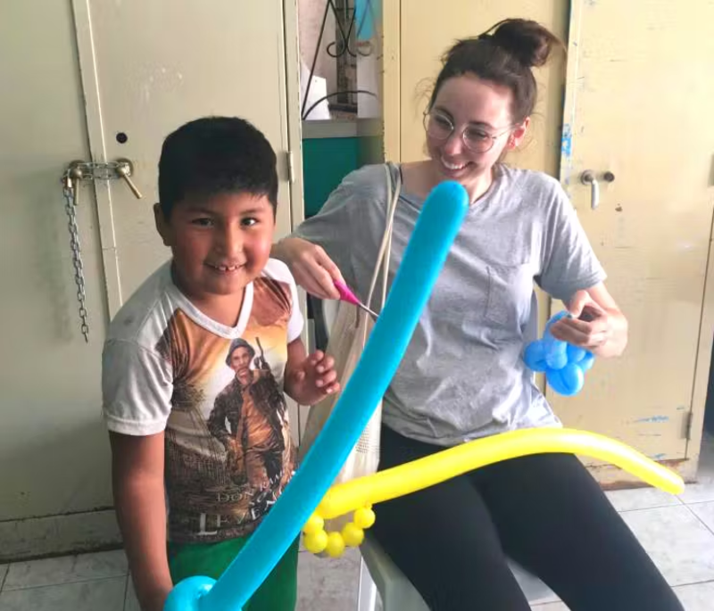 IVHQ Volunteer and child playing with balloon swords