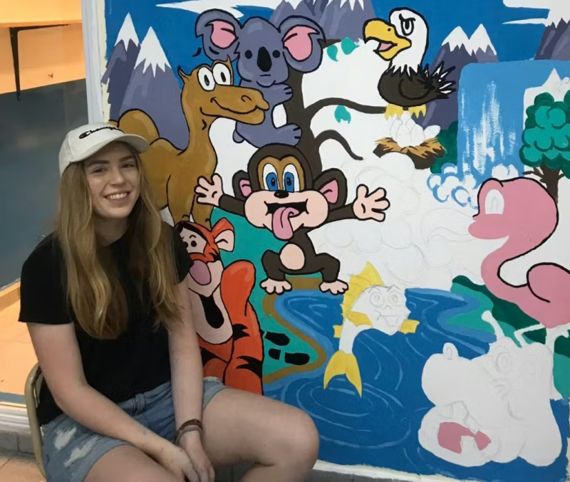 IVHQ Volunteer sitting next to their freshly painted mural