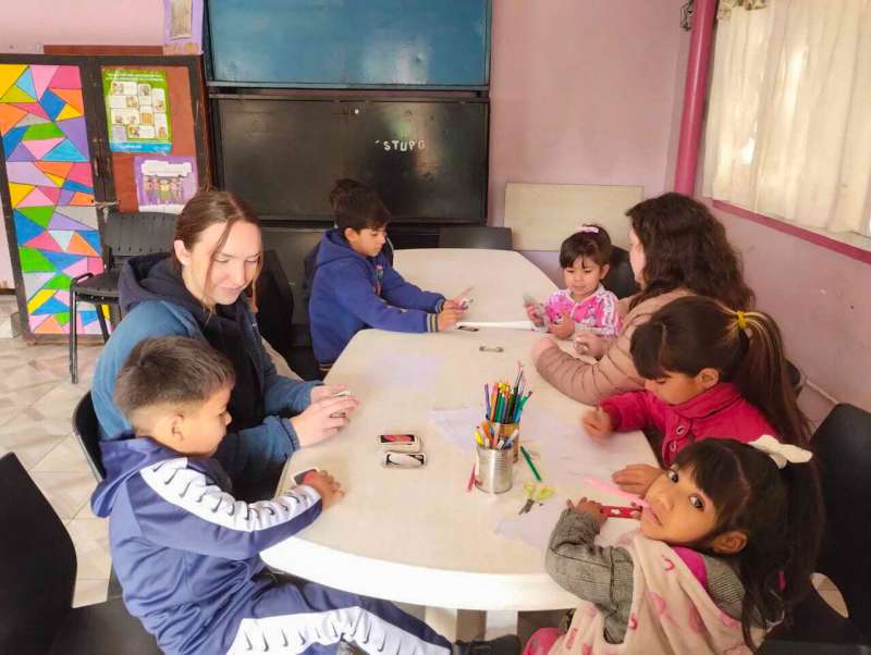 IVHQ Volunteers coloring and playing uno with a group of children 