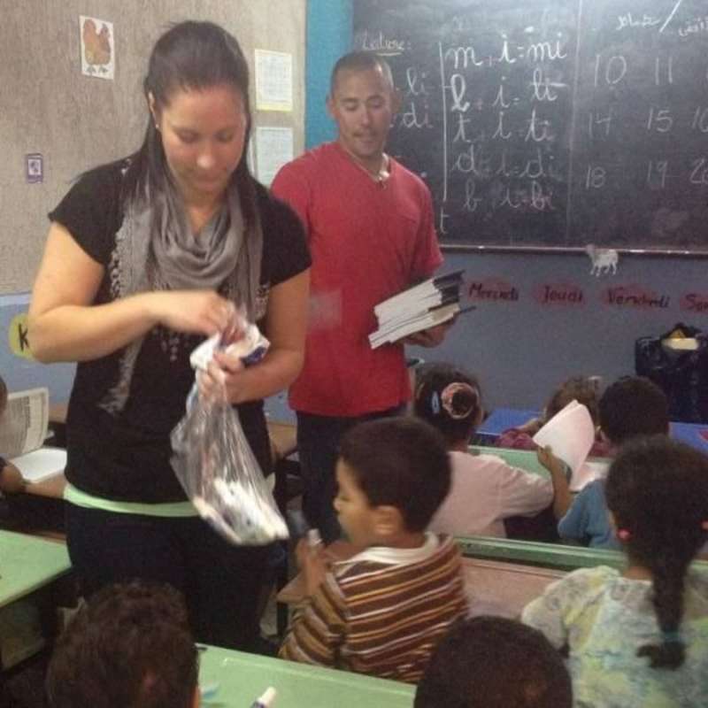 A volunteer hands out resources to a class in Morocco