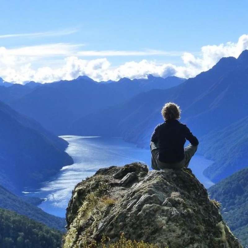 student seated looking over lake and mountains