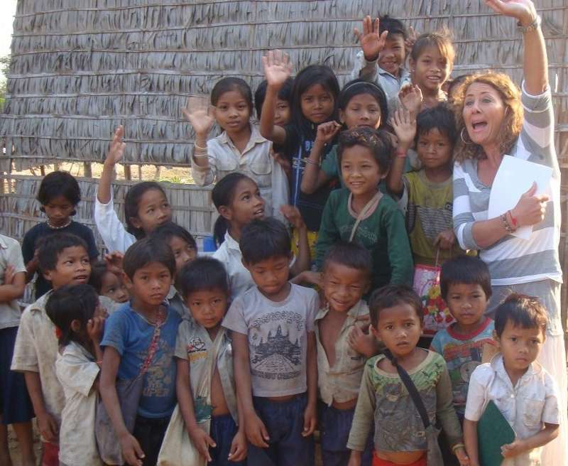 Volunteer raising her hand on a group photo with kids