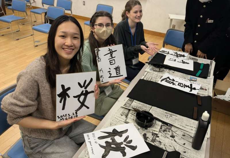 Semester abroad teens holding up their kanji in a classroom