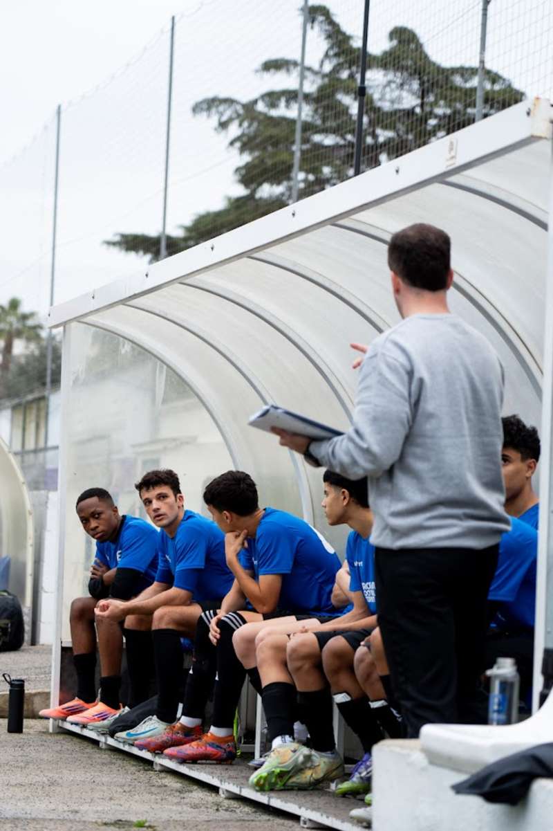 soccer players at the bench listening to their coach