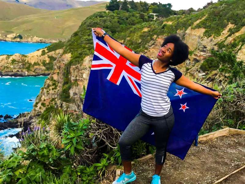 student holding a New Zealand flag behind them while on a nature hike
