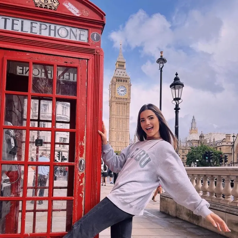 Student in front of Big Ben next to a red phonebox. 