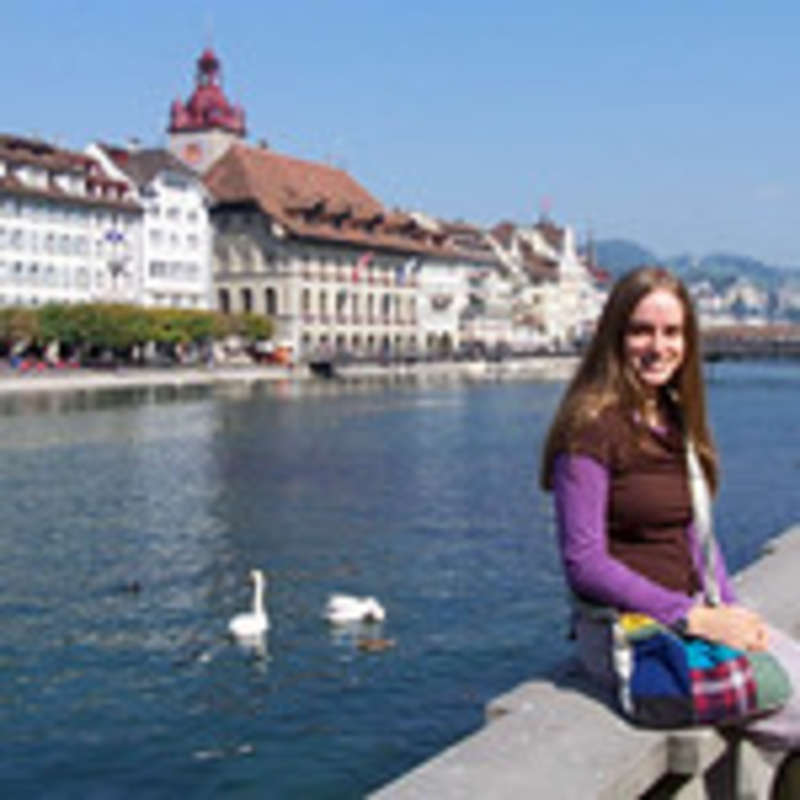 Student in front of canal with birds and houses in the background