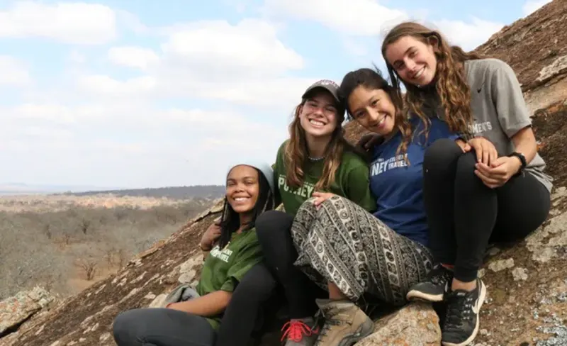 Student pose for group photo on rock ledge