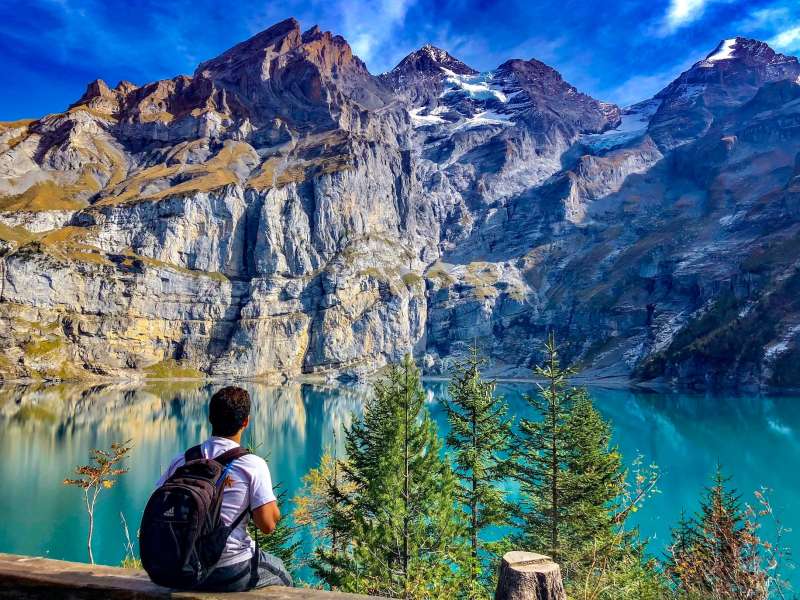 Student sitting in front of lake and mountains in Switzerland