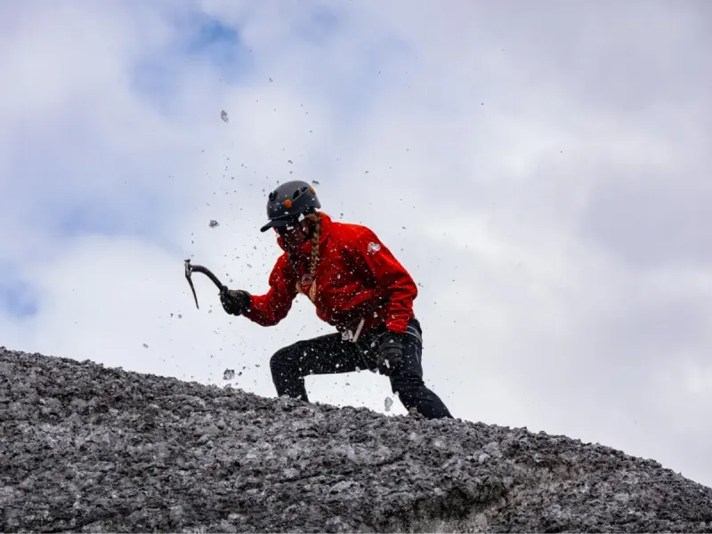 Student swings ice axe on mountain