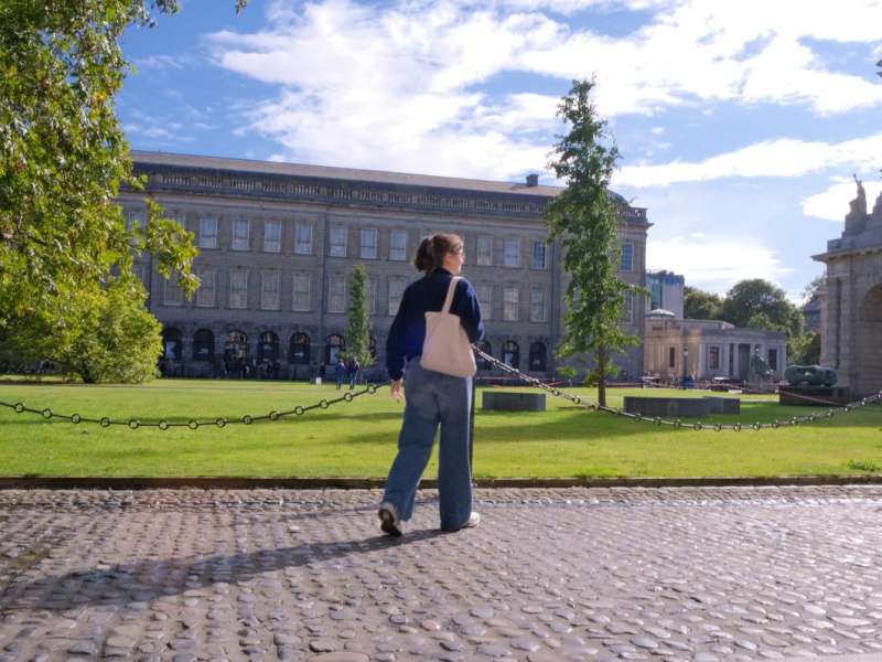 Student walking alone on Trinity campus on a sunny day