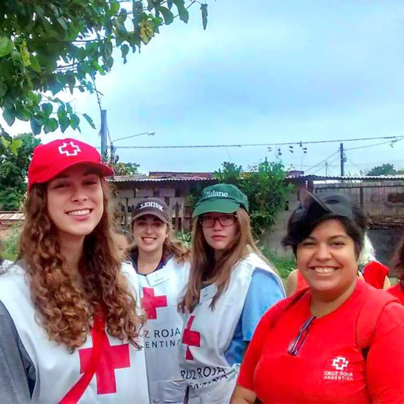 Students and healthcare workers wearing medical aprons with a red cross and baseball caps.