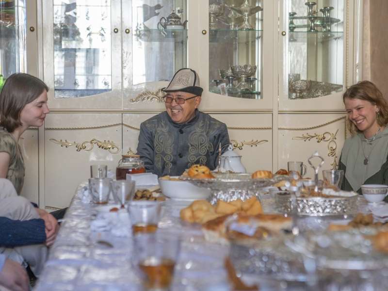 Students at a table with a man in traditional dress
