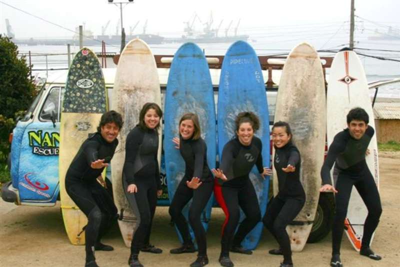 Students catching waves on a sunny Chilean beach during an English program surf excursion.