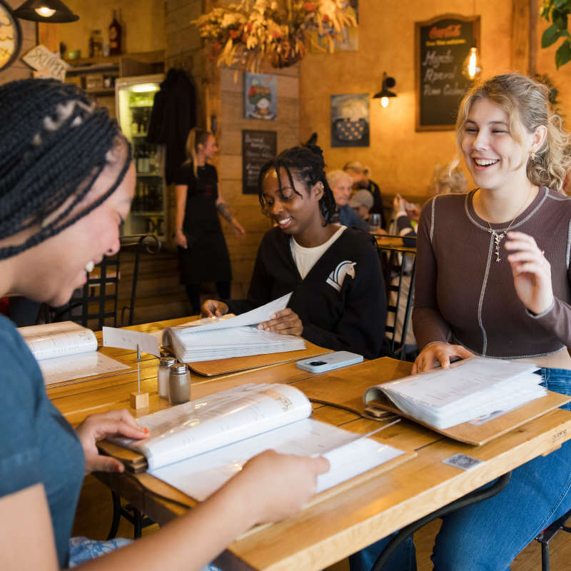 Students chat and study in a cafe. 