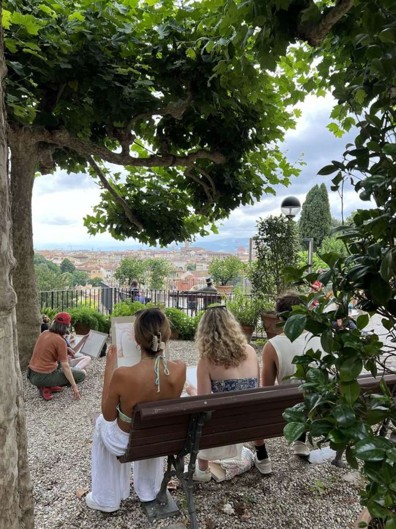 Students drawing in garden in Italy overlooking city skyline