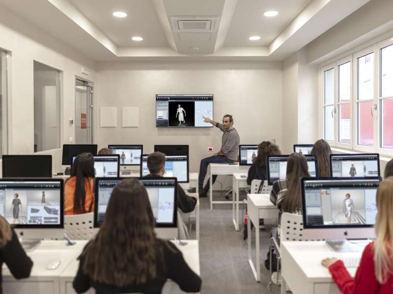 Students facing the teacher and sat at desks with computers