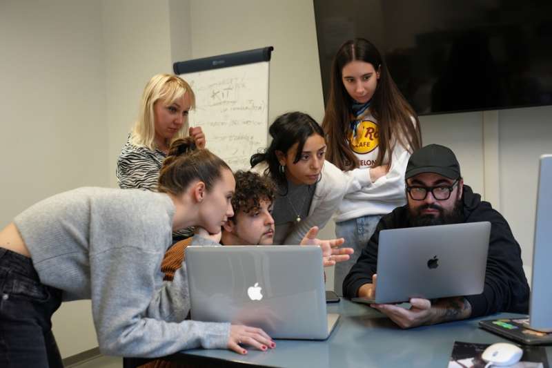 Students gathered around 2 laptops in a classroom