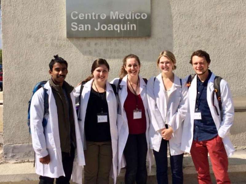 students in physician's coats in front of their clinical placement