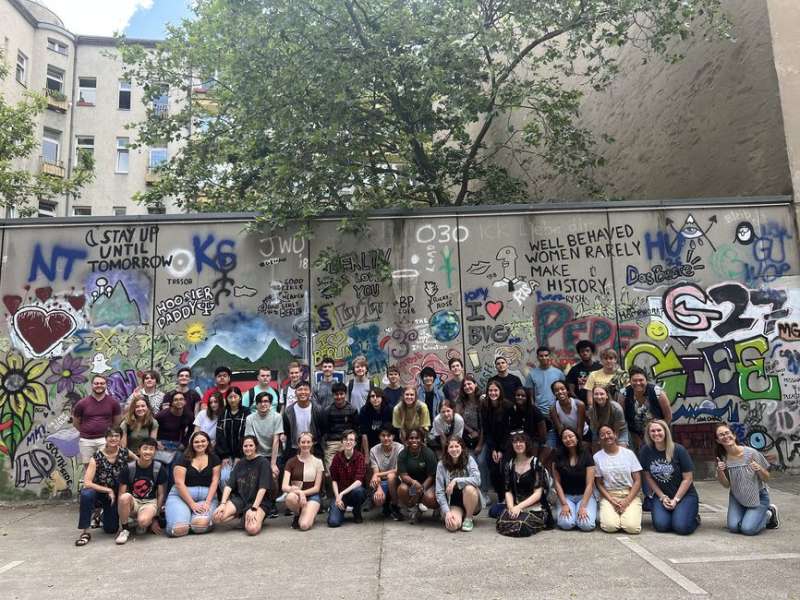 Students posing in front of Berlin graffiti wall