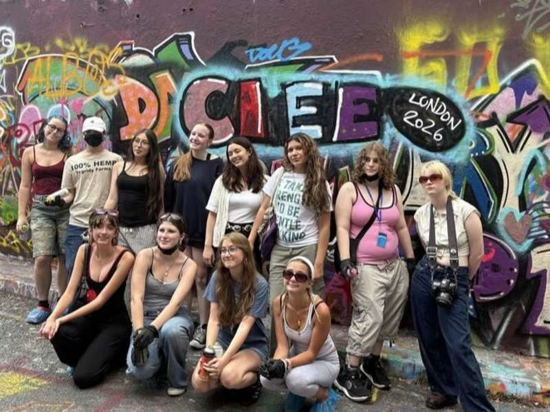 Students posing in front of graffiti wall in London