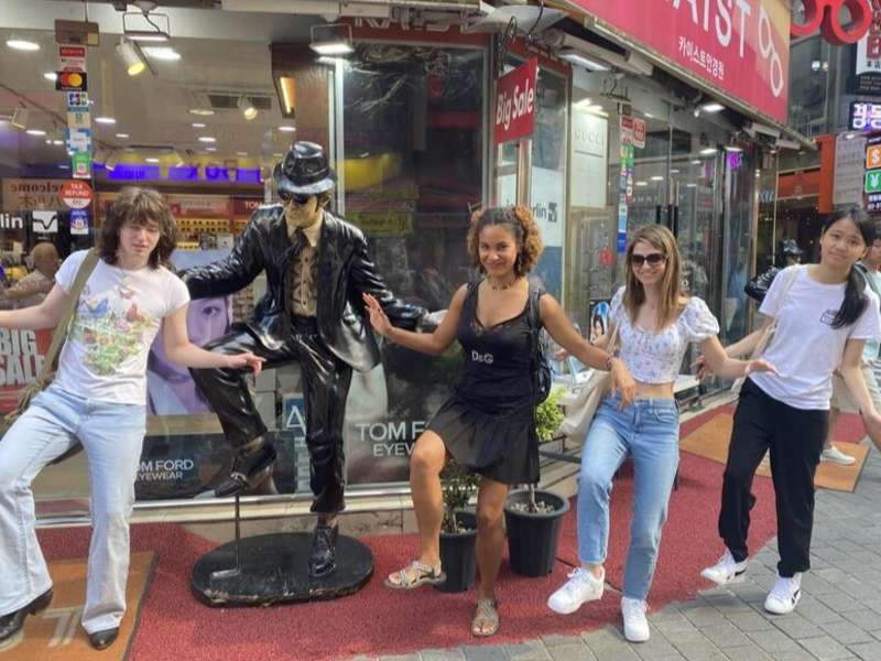 Students posting with statue on program in Seoul