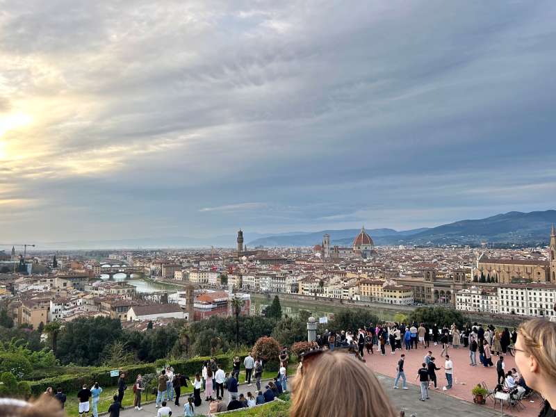 Students sitting at overlook above Florence cityscape at dusk