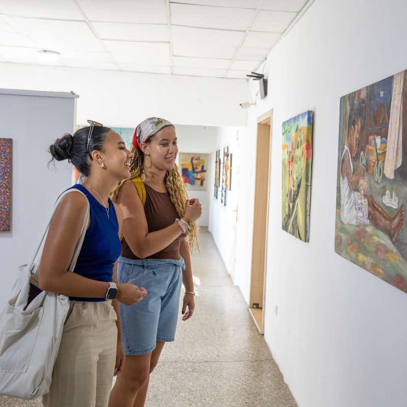 Students smile in front of a painting.