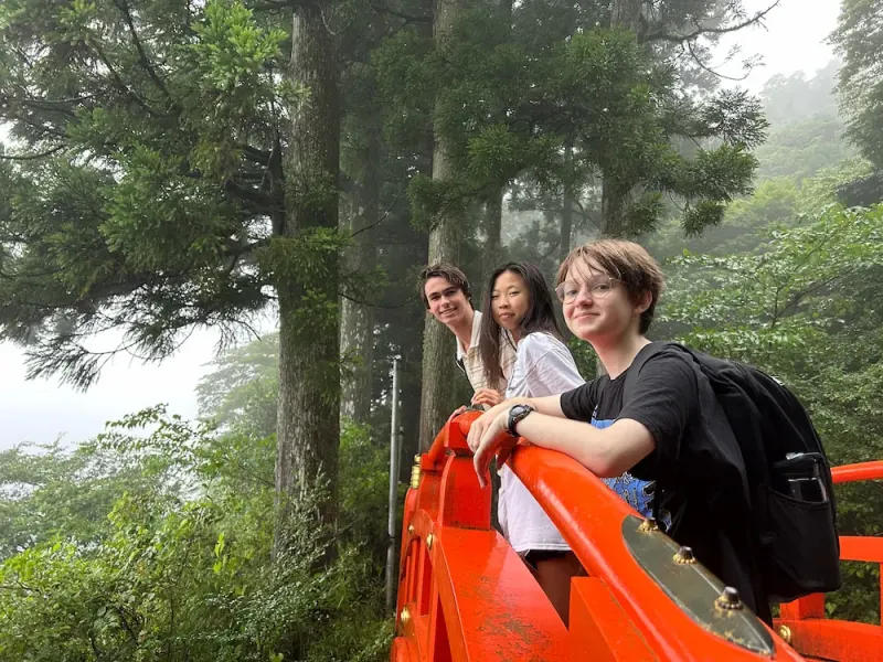 Students stand in forest on bridge in Japan