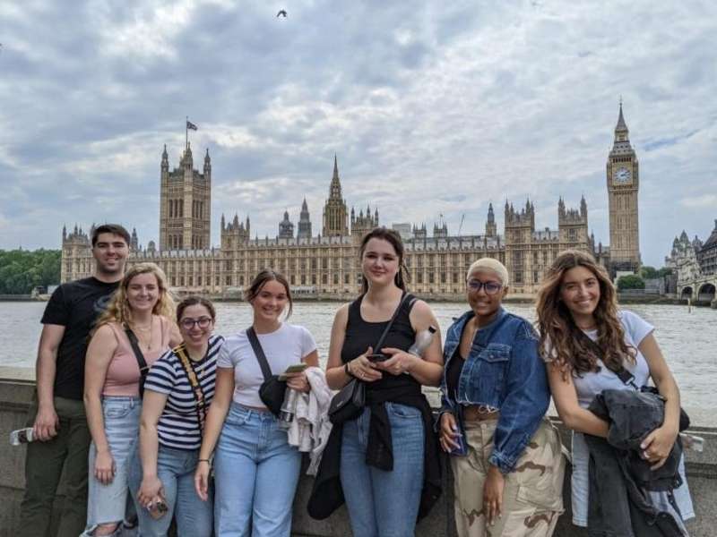 Students standing along the River Thames with the Houses of Parliament and Big Ben in the background.