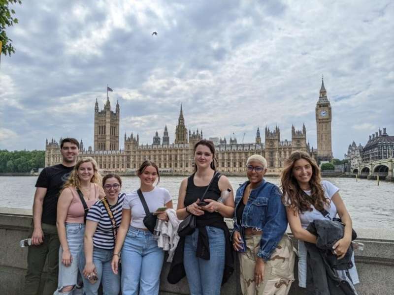 Students standing along the River Thames with the Houses of Parliament and Big Ben in the background.