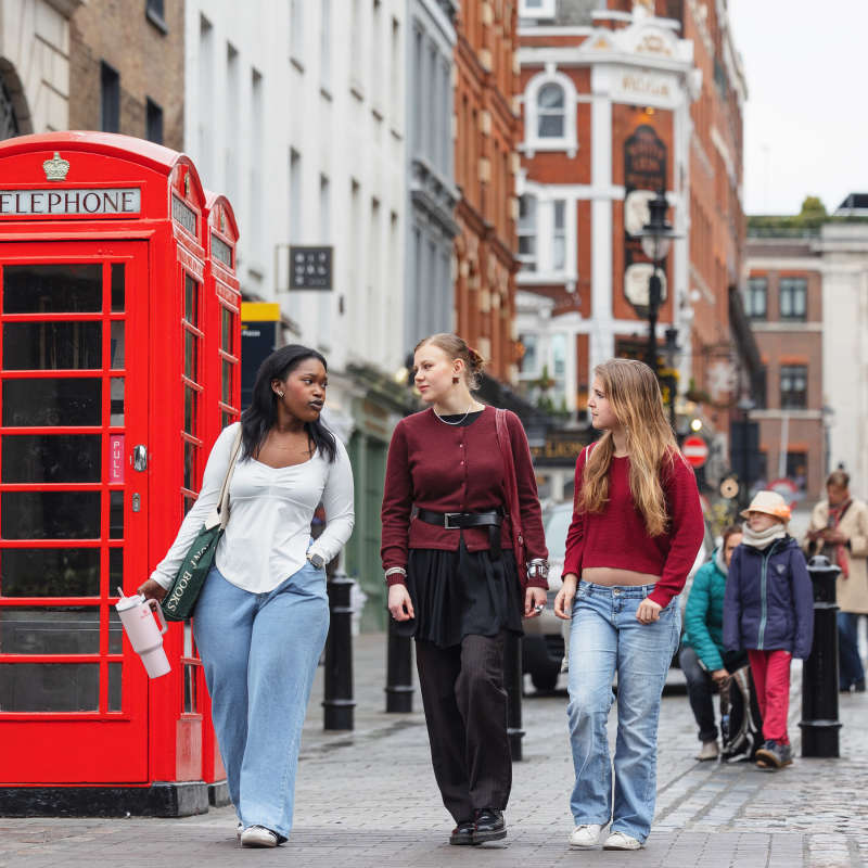 Students walking in the city with a telephone booth in the background.