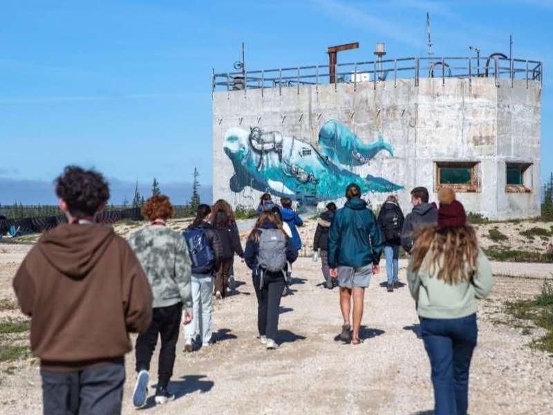Students walking to research center with Beluga mural in Canada