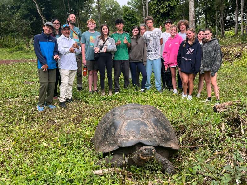 students with a giant tortoise in the Galapagos on a teen travel program