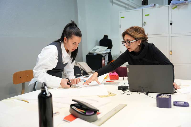 Teacher helping student with project in fashion design classroom