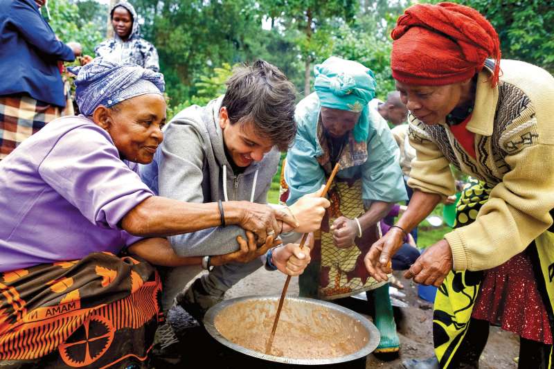 Teen boy cooking with locals in Tanzania